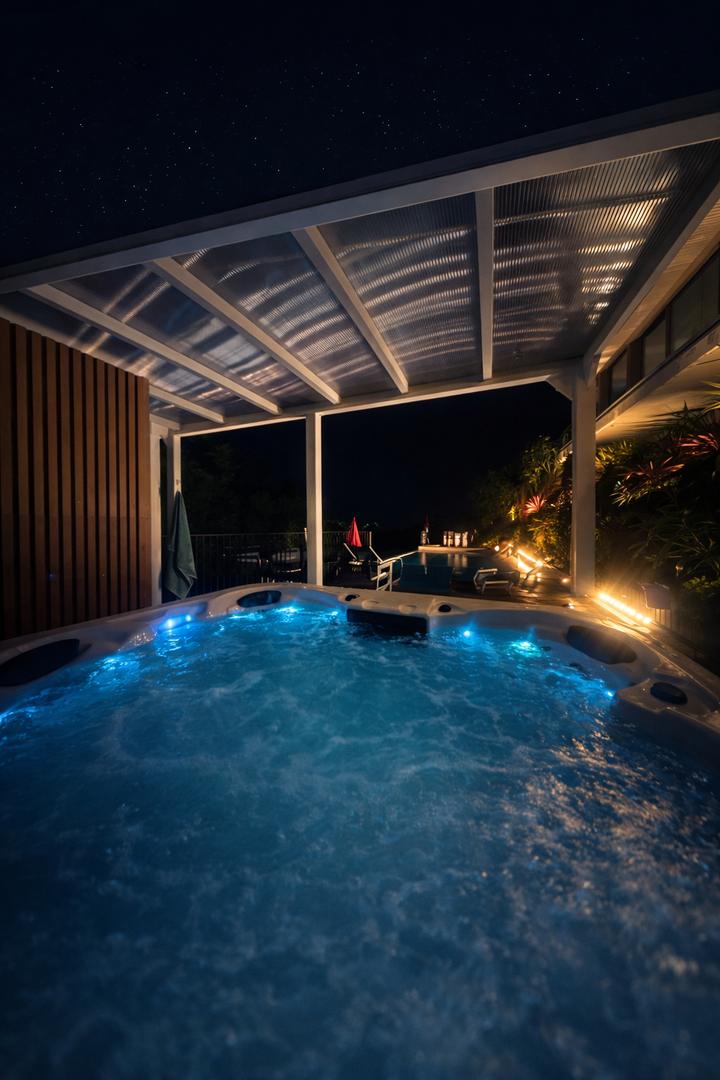 Jacuzzi éclairé la nuit sous la pergola, ciel étoilé
