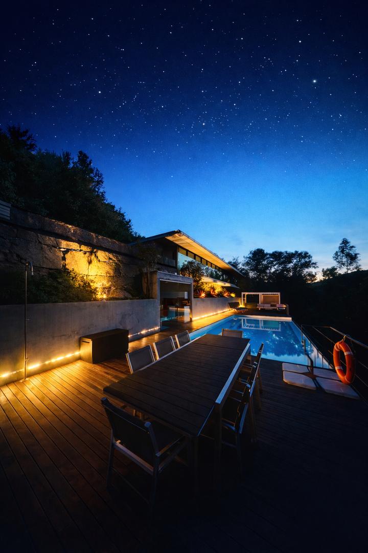 Table dressée sur la terrasse et piscine éclairée sous les étoiles