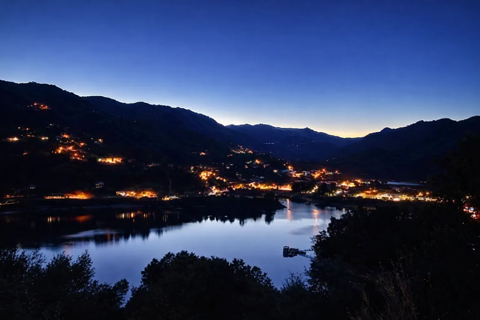Le lac de Caniçada et les lumières de Rio Caldo à la tombée de la nuit