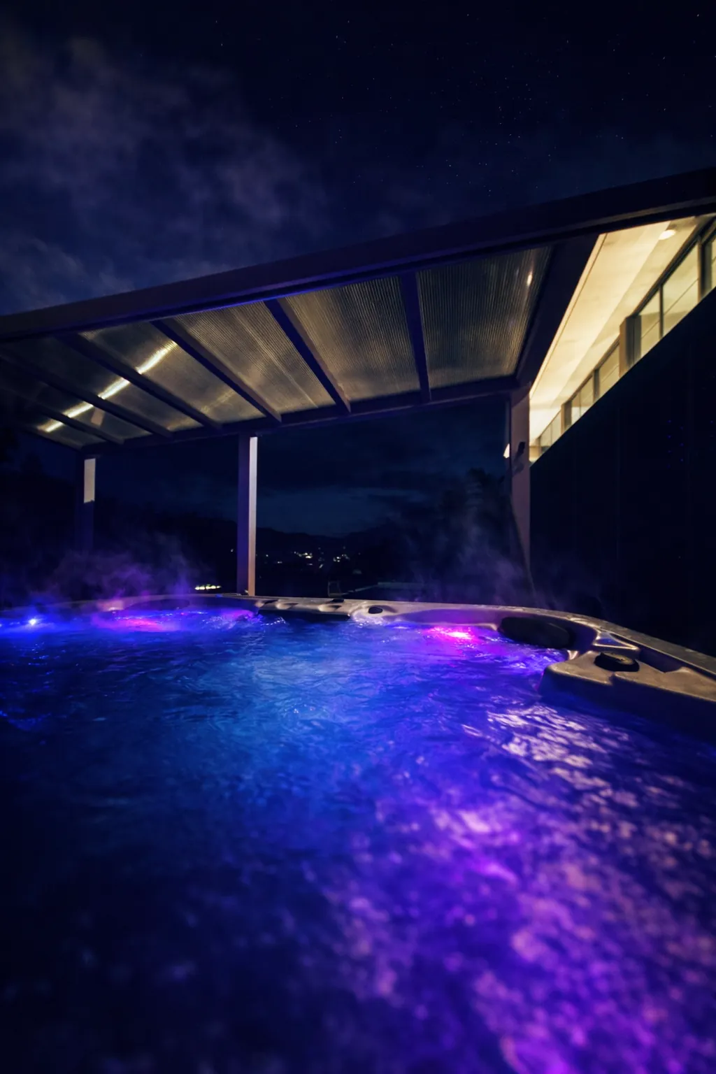 Jacuzzi illuminé la nuit sous la pergola